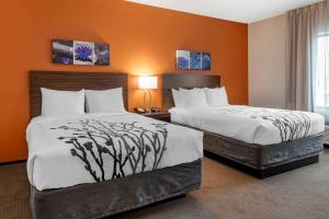 two beds in a hotel room with orange walls at Sleep Inn & Suites Moab near Arches National Park in Moab