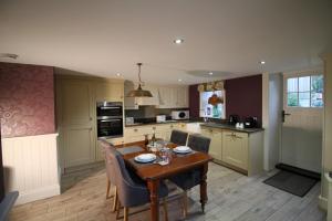 a kitchen with a wooden table with chairs and a dining room at Drake Cottage in Whitby