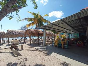 una playa con un pabellón, mesas y sillas en NICO'S BEACH PANAMA en Playa Blanca