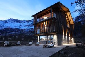 a building with a balcony with chairs and mountains at Chalet Blanc in Breuil-Cervinia