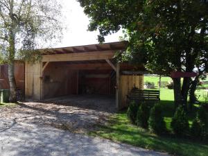 a wooden garage with a fence and a tree at Casa Emmi in Bad Mitterndorf