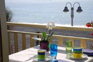 a table with plates and glasses on a balcony with the beach at Hotel Piccolo Paradiso in Bordighera