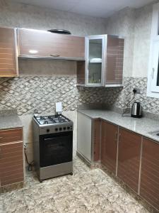a kitchen with a stove and wooden cabinets at Taj Alarfeen Furnished Building in Salalah