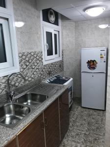 a kitchen with a sink and a refrigerator at Taj Alarfeen Furnished Building in Salalah