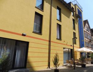 a yellow building with a red stripe on it at Hotel Gasthof zum Engel in Künzelsau