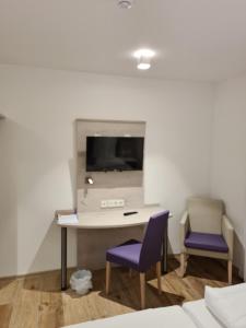 een kamer met een bureau en 2 paarse stoelen bij Hotel Gasthof zum Engel in Künzelsau