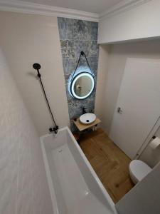 Panoramic Apartments Oradea في أوراديا: حمام مع حوض استحمام أبيض ومرآة
