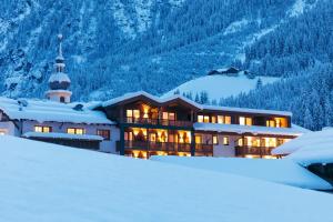 ein Gebäude im Schnee mit einem Berg in der Unterkunft Hotel Kirchenwirt in Kaunertal