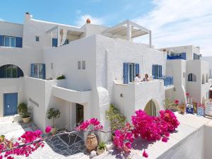 Un edificio blanco con flores rosas delante. en Iria Beach Art Hotel, en Agia Anna de Naxos