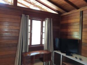 Una sala de estar con televisión y una ventana. en Chalezinho Pedra Azul, en São Pedro da Serra