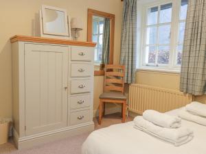 a bedroom with a dresser and a chair at East Cottage - Tarvit in Cupar