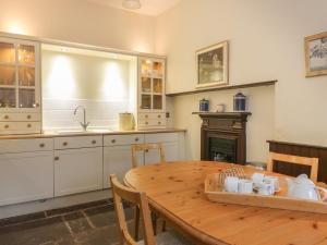 a kitchen with a wooden table and a fireplace at Harmony Cottage - Harmony Gardens in Melrose