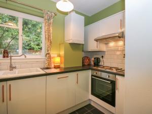 a kitchen with white cabinets and a sink and a window at Branklyn Garden Cottage in Perth