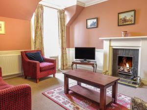 a living room with a tv and a fireplace at Upper West Wing Flat - Tarvit in Cupar