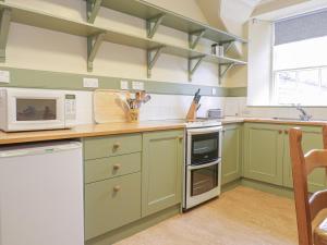 eine Küche mit grünen Schränken und einer Mikrowelle in der Unterkunft Upper West Wing Flat - Tarvit in Cupar