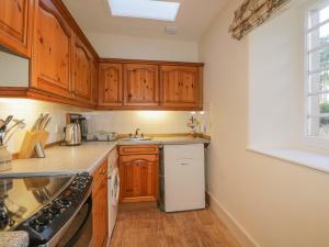 a kitchen with wooden cabinets and a white refrigerator at Cormack Lodge - Brodie Castle in Forres