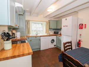 uma cozinha com armários verdes e um frigorífico branco em Blue Door - Kirkcudbright em Kirkcudbright