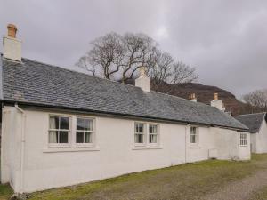 une maison blanche avec deux cheminées au-dessus dans l'établissement Stalker's Cottage - Torridon, à Achnasheen