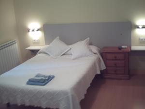 a bedroom with a white bed with two towels on it at Pensión la Marinera in San Sebastián