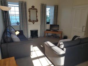 uma sala de estar com dois sofás e uma televisão em Royal Artillery Cottage - Culzean Castle em Maybole