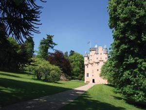 ein Schloss inmitten eines üppigen grünen Feldes in der Unterkunft Steading Cottage - Craigievar Castle in Alford