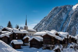 une église recouverte de neige devant une montagne dans l'établissement Panorama A, à Blatten bei Naters