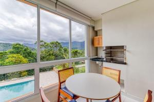 a kitchen with a table and chairs and a large window at C15 - Conforto junto a natureza - Camburyzinho in São Sebastião