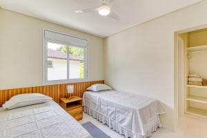 um quarto com 2 camas e uma janela em D16 - Conforto junto a natureza - Praia de Camburyzinho em São Sebastião