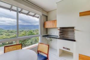 a kitchen with a table and chairs and a large window at D16 - Conforto junto a natureza - Praia de Camburyzinho in São Sebastião