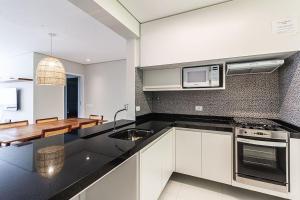a kitchen with white cabinets and a sink and a microwave at A12 -Conforto junto a natureza - Praia de Camburizinho in São Sebastião