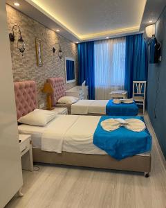 Dos camas en una habitación de hotel con cortinas azules. en elisa apart 3, en Estambul