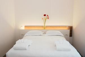 1 cama blanca con 2 almohadas y un jarrón con flores en Toscana Charme Resort en Tirrenia