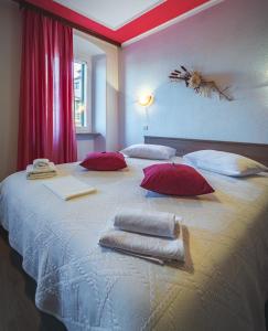 un grande letto bianco con cuscini rossi e asciugamani di Guest House Nena a Motovun (Montona)