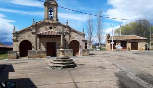 una antigua iglesia de piedra con una torre de reloj en una calle en Hotel Rural Molino del Arriero, en Luyego de Somoza