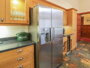 a stainless steel refrigerator in a kitchen with wooden cabinets at Bynack - Mar Lodge Estate in Ballater