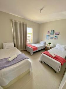 a bedroom with two beds and a window at Condomínio Villa das Aguas com wi-fi in Praia do Saco +51 photos