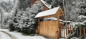 a wooden cabin in the snow with a gate at Cabana Ancutei in Rucăr