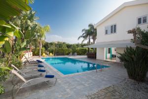 - une piscine avec des chaises longues à côté d'une maison dans l'établissement Papaya Royal Villa, à Ayia Napa