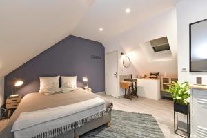 a bedroom with a large bed with a blue wall at Chambres d'hotes Les Nuits Pastel in Saint-Quentin