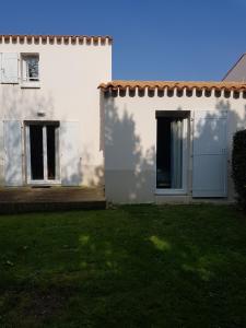 une maison blanche avec deux fenêtres et une cour dans l'établissement ARRETEZ VOUS A OLERON, au Château-dʼOléron