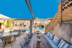 a patio with a wooden table and chairs and a pool at Garden Village Studios & Apartments in Kalamaki