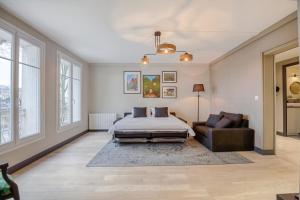 1 dormitorio con cama, sofá y ventanas en Le Gambetta - T3 Standing avec Parking, Wifi, Netflix en Laval