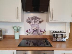 a painting of a cow on the wall of a kitchen at Inviting 2-Bed Barn with hot tub near Muirkirk in Cumnock