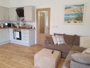 a living room with a couch and a kitchen at Inviting 2-Bed Barn with hot tub near Muirkirk in Cumnock