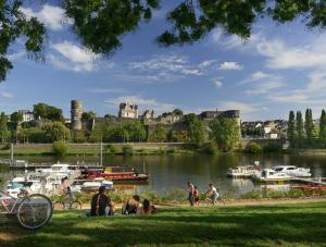 Des gens assis sur l'herbe près d'une rivière avec des bateaux dans l'établissement Hyper Centre rue de la Roe, à Angers