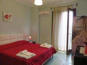 Un dormitorio con una cama roja con toallas. en Case Vacanze Residence Trinacria, en Acireale
