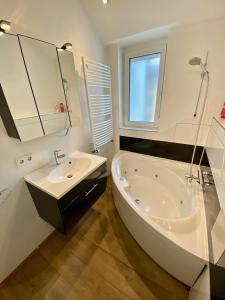 a white bathroom with a tub and a sink at Luxuriöses Studio im Zentrum, Balkon, Kamin, Klima in Ravensburg