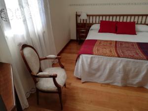 Un dormitorio con una cama con almohadas rojas y una silla en Hotel Rural Molino del Arriero, en Luyego de Somoza