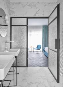 a bathroom with a tub and a sink and a bedroom at Amosa Liège City Centre Hotel in Liège