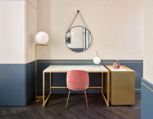 una scrivania con sedia rosa e specchio di Amosa Liège City Centre Hotel a Liegi
